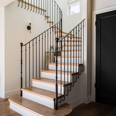 elongated balusters that attach to black stair railing with wood steps