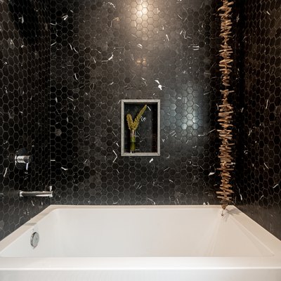 white bath/shower combination, black hexagon tile with white dashes, hanging wooden decoration