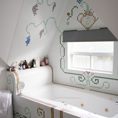 jetted tub with decorative tile surrounding it, bath products on the tub ledge