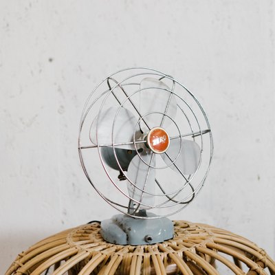 Small oscillating fan on rattan side table