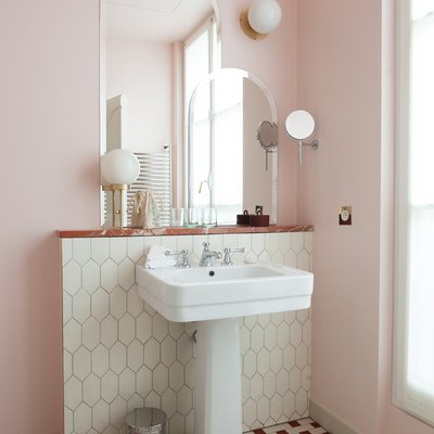 pedestal bathroom sink with pink walls and patterned floor tile
