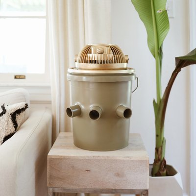 Green and gold portable bucket air conditioner on an end table next to a couch