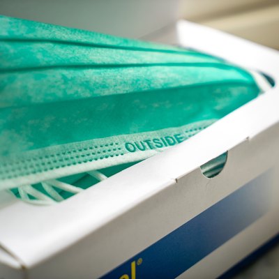 white box filled with teal disposable face masks