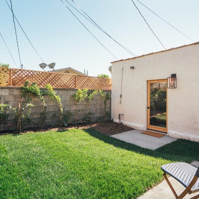 Spanish-style home with a green, freshly mowed yard; a concrete block fence and a blue patio chair are seen in the pho