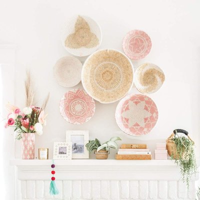 Seven decorative woven bowls featuring white, beige, and light pink hues on wall