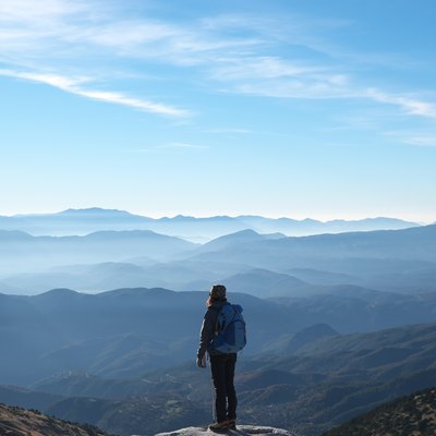 person standing on a tall precipice overlooking a natural view