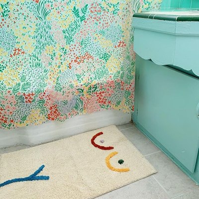 teal bathroom with cream bath mat