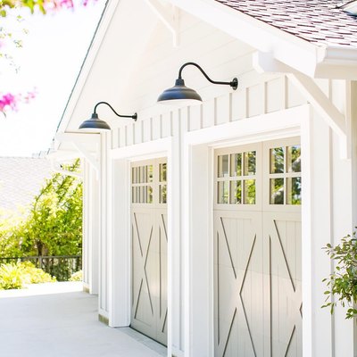 Cream barn garage doors with white exterior and black barn lights