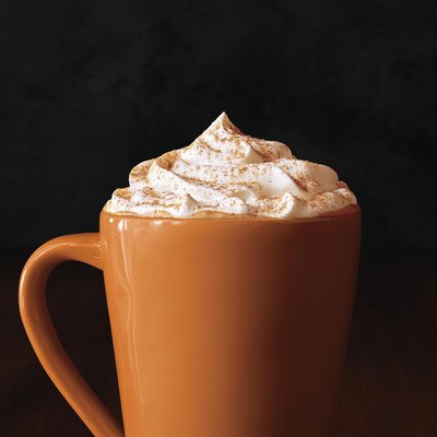 tall orange mug filled with pumpkin spice latte and whipped cream