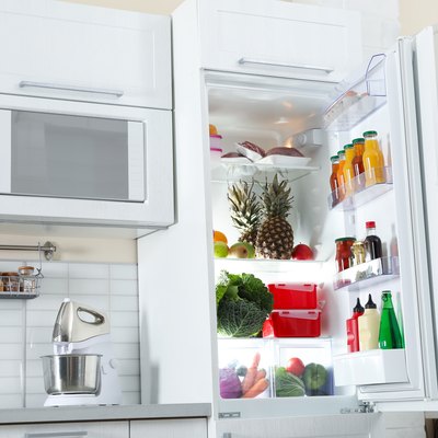 Open refrigerator full of products in stylish kitchen interior