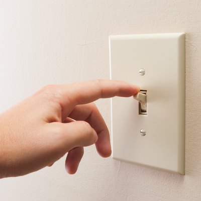 Hand turning wall light switch off
