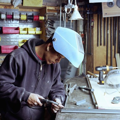 Young workman welding joint on metal frame