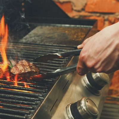Man cooking meat steaks on professional grill outdoors