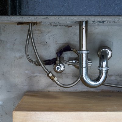Bathroom steel sink pipes, trap and drain on concrete wall
