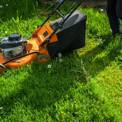 A man mowing grass with a mow in a farm yard