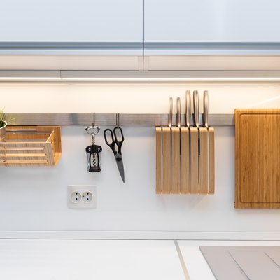 kitchenware hanging on the rail in the white glossy kitchen