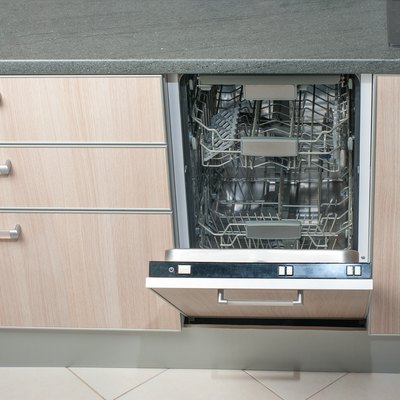 Open empty dishwasher in kitchen. Modern smart electronic housekeeping technology