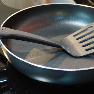 Metal black frying pan with a non-stick coating on electric stove