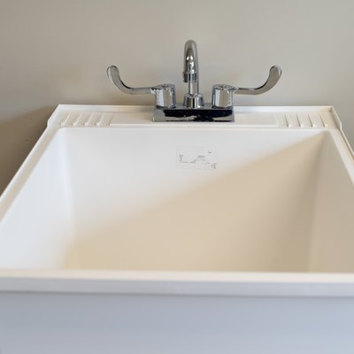 White plastic laundry sink, turned off, in a laundry room