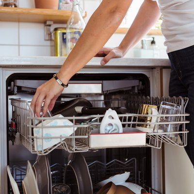 Midsection of woman using dishwasher while standing in kitchen