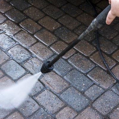 Guy using a pressure washer on courtyard with paving stone