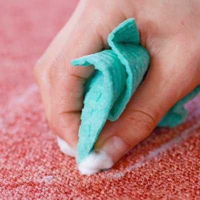 cleaning red carpet floor with rag and hand