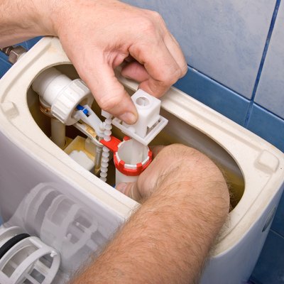 Plumber repairing the mechanism of a toilet