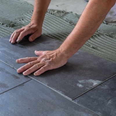 Worker installing ceramic floor tiles