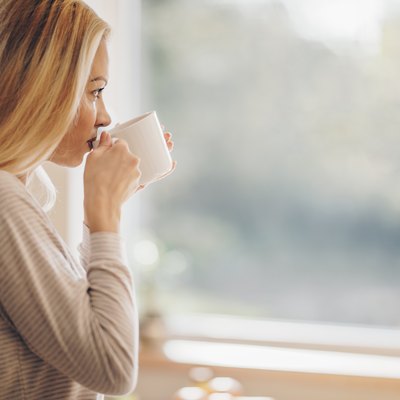 Profile view of pensive woman drinking morning coffee at home.