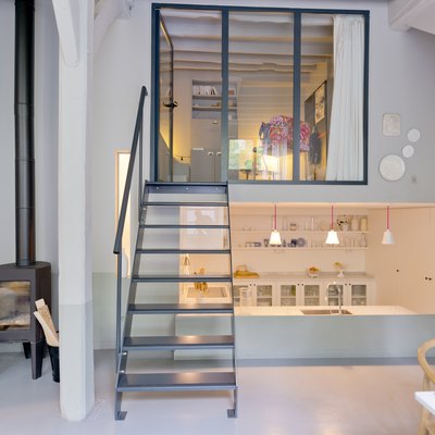 Small living room and kitchen up the stairs and dawn in fashionable loft studio apartment.