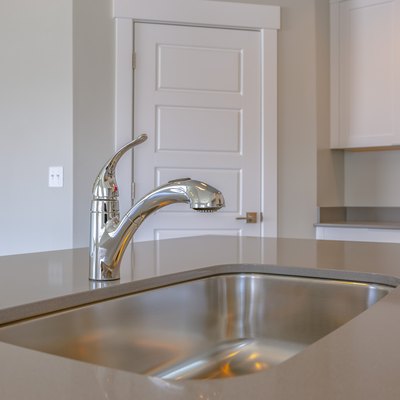 Shiny stainless steel sink and faucet on the countertop inside a kitchen