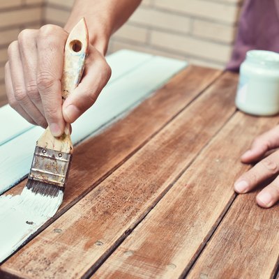 young man painting an old wooden table