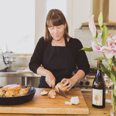 Woman cutting onion on cutting board at table