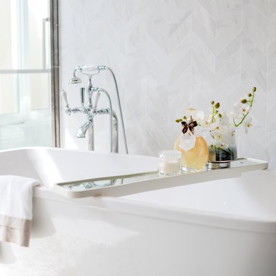Closeup chrome faucet and showerhead, white bathtub.