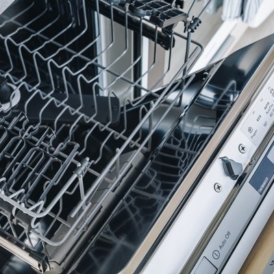 Open empty dishwasher machine close-up in modern kitchen.
