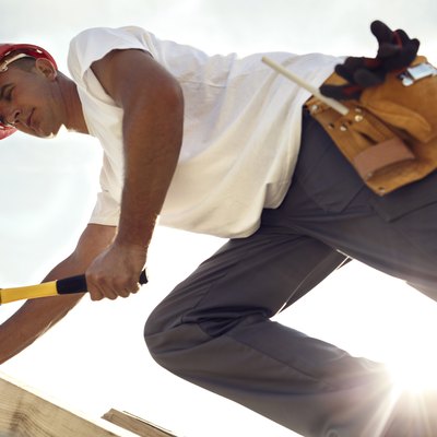 Construction roofer nailing wood board with hammer