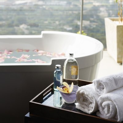 Towels, aromatic oils and orchid next to bathtub