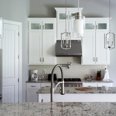 Interior design and kitchen architecture decorated with white wooden furniture, marbled materials and built in appliances