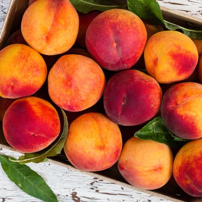 Fresh organic peaches in wooden crate.