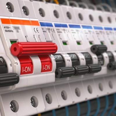 Switches in fusebox. Many black circuit brakers in a row in position OFF and one red switch in position ON.
