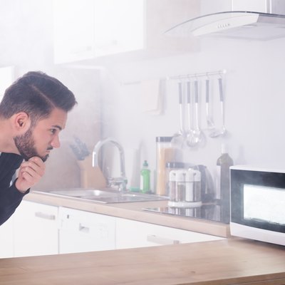 Man Spraying Fire Extinguisher On Microwave Oven