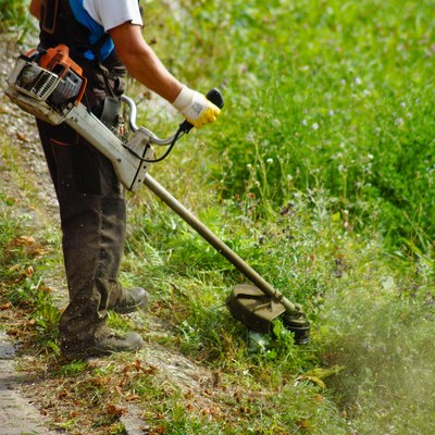 Low Section Man Cutting Grass With Strimmer In Yard