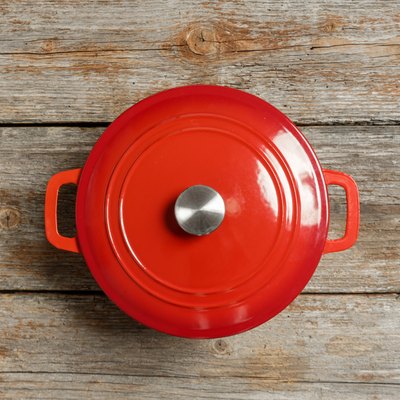 Top view of red enameled iron stockpot on wooden background