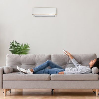 African female lying on couch use airconditioner breathing fresh air