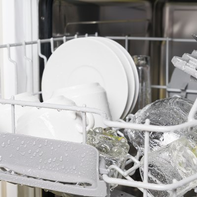 wet clean white dishes and cutlery are in the dishwasher