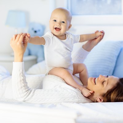 Mother and baby on a white bed.