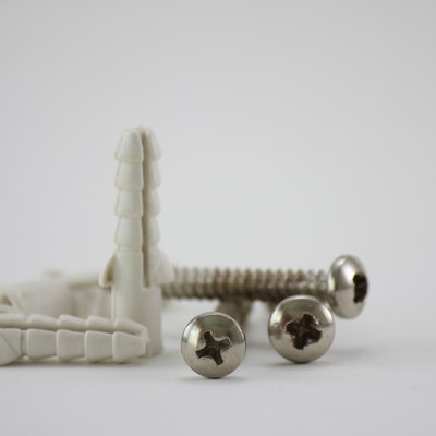 Close-Up Of Screws With Hollow Wall Anchors Over White Background