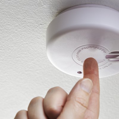 Close Up Of Hand Testing Domestic Smoke Alarm