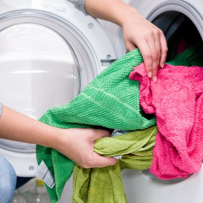 Midsection Of Woman Putting Clothes In Washing Machine