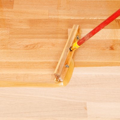 Squeegee Style Brush Applying Clear Polyurethane to Hardwood Floor